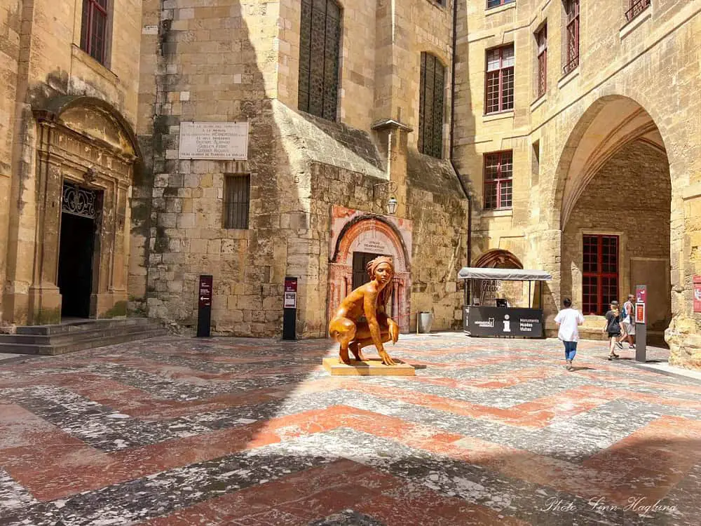 A bronze statue of a woman in medieval Narbonne old town.