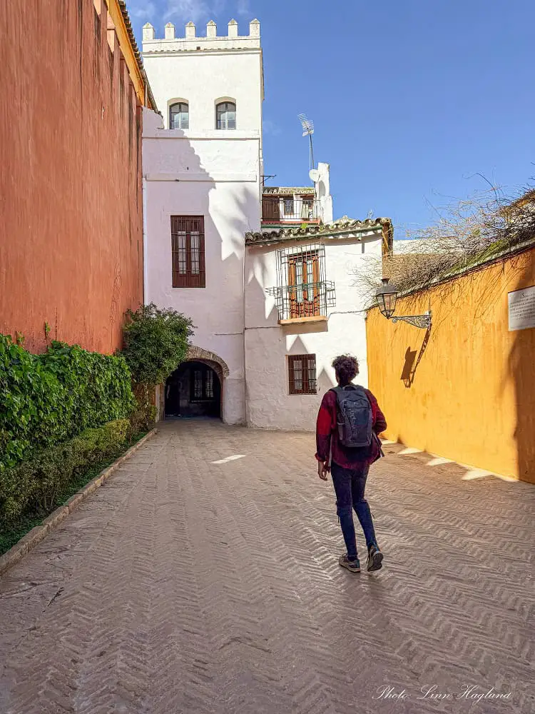 Mohammed walking through an empty, colorful street in Barrio de Santa Cruz in Seville. This is the old Jewish Quarter of Seville and walking through the narrow maze-like streets is one of the must-do's in Seville.