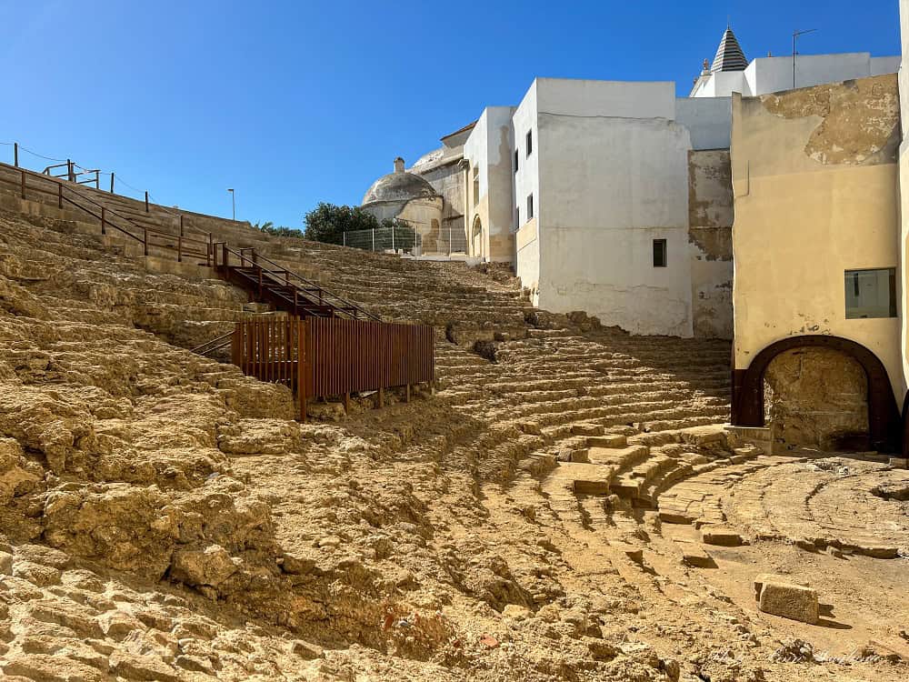 The old Roman Theater in Cadiz with worn seats for spectators, which has houses built into it. Visiting the Roman Theater is free and a must on any 1 day in Cadiz sightseeing trip.
