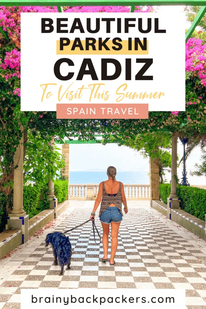 Me and Ayla walking on a check-colored patio under pink flowers towards a sea view. This is one of Cadiz's parks that are so worth visiting in southern Spain.