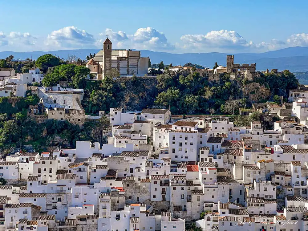 Whitewashed houses of Casares Spain cascading down a hillside on a sunny day.