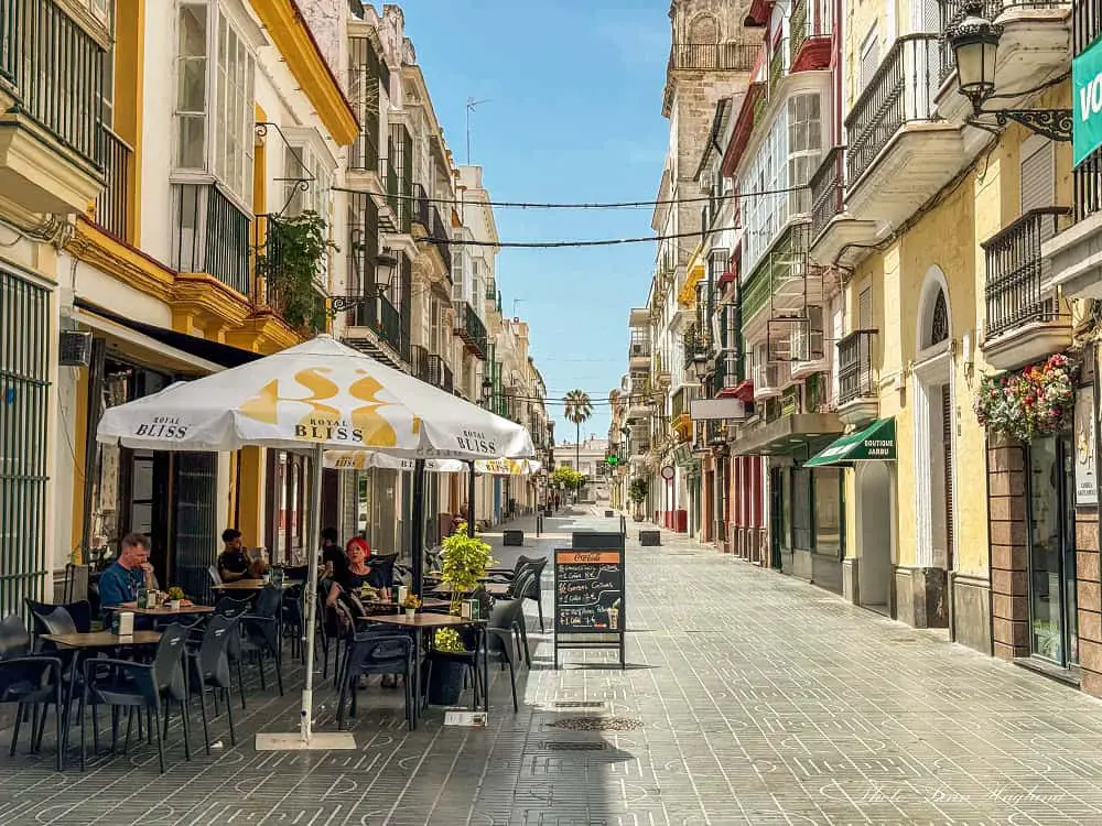 People having tapas and drinks in a bar in El Puerto de Santa Maria, Spain. It's a hot, sunny day, and the street is almost empty.
