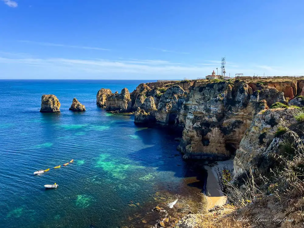 Rugged coast of Algarve with boats and kayaks.