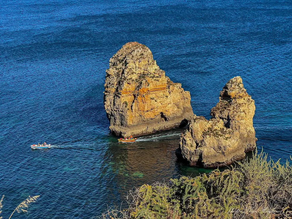 Speed boats between rugged cliffs in the ocean.