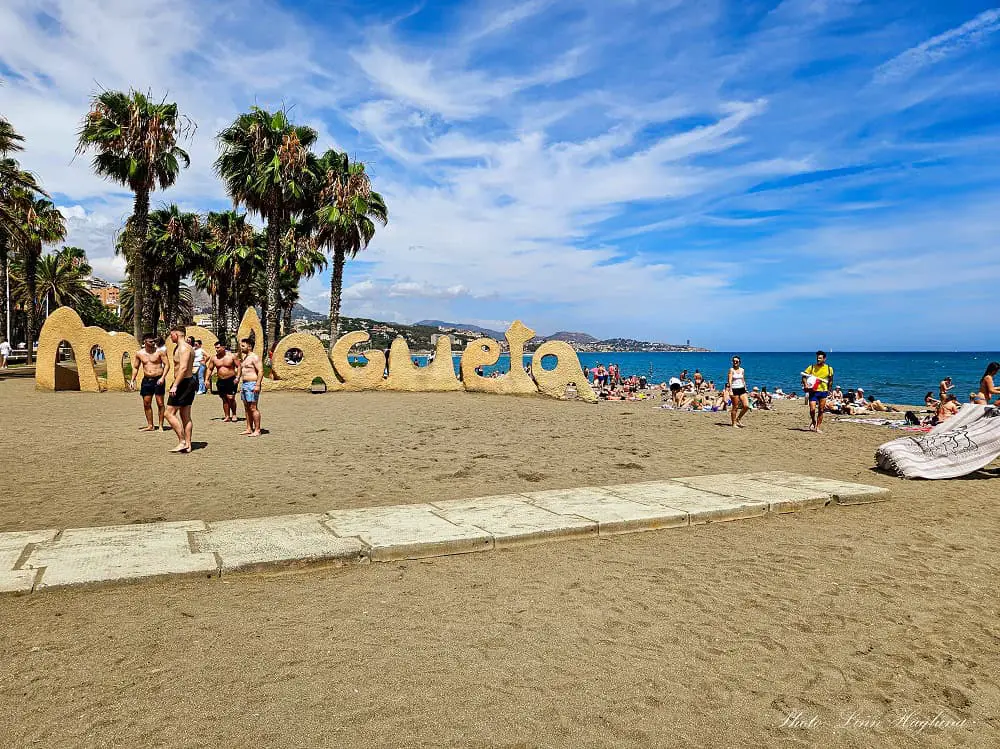 Malagueta beach Malaga in spring with people sunbathing on the beach by the Malagueta sign.