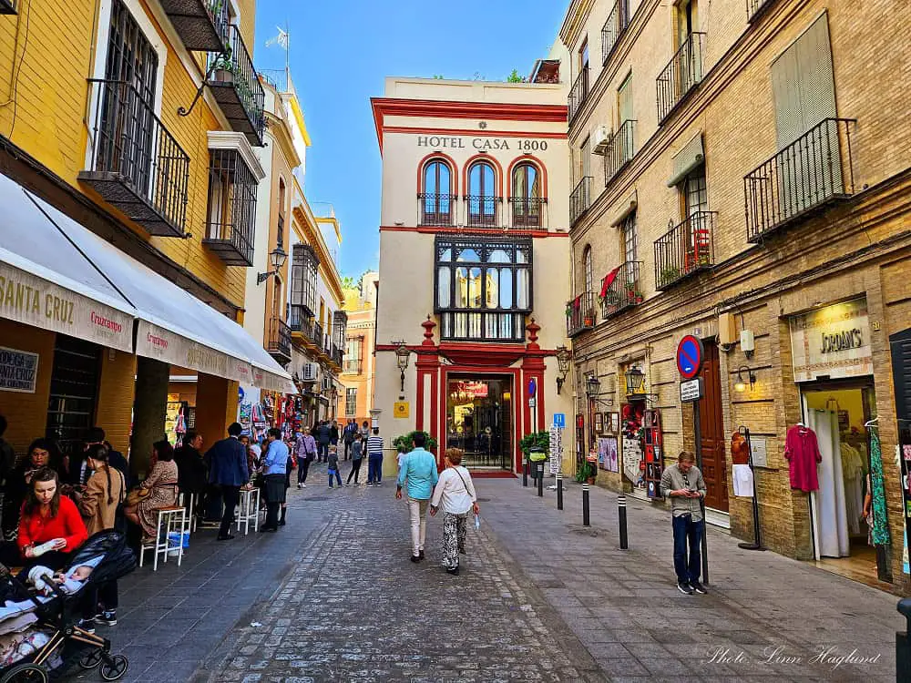 A bustling street in old town Seville with hotels, which is where to stay in Seville Spain.