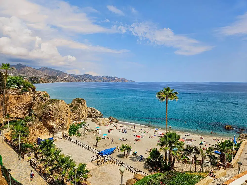 Beautiful beach in a cove with turquouse water and people swimming.