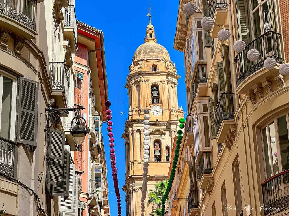 A church tower seen at the end of a narrow street in Malaga Old Town.