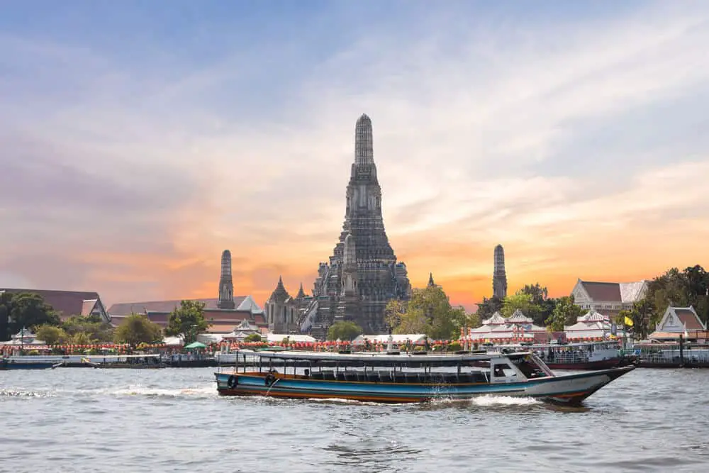 River cruise passing Wat Arun in Bangkok at sunset