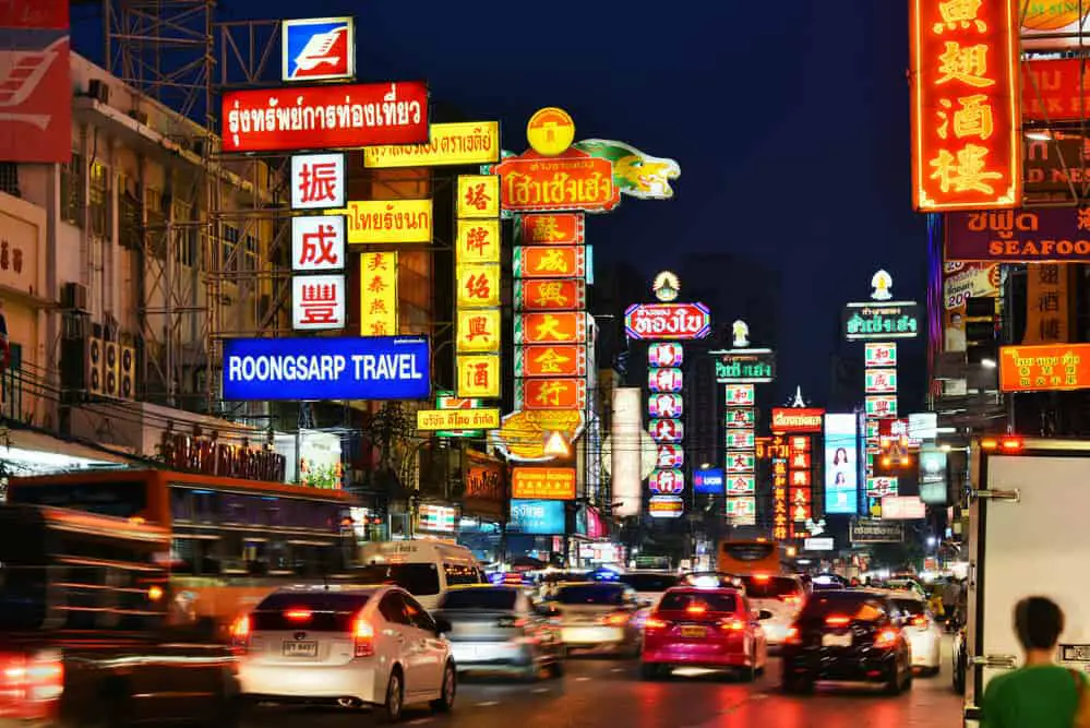 Yaowarat Road in Bangkok's Chinatown at night with colorful signs lighting up the street.