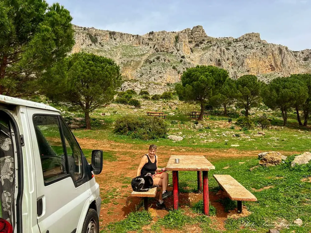 Me and my dog sitting on a bench outsie our van with a backdrop of mountains.