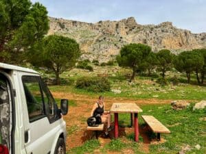 Campervanning in Spain: Our puppy Atlas and me sitting outside the van in natural environment with mountains behind us.