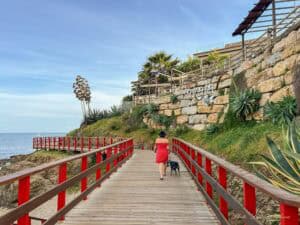 Me walking along Mijas boardwalk in a red dress.