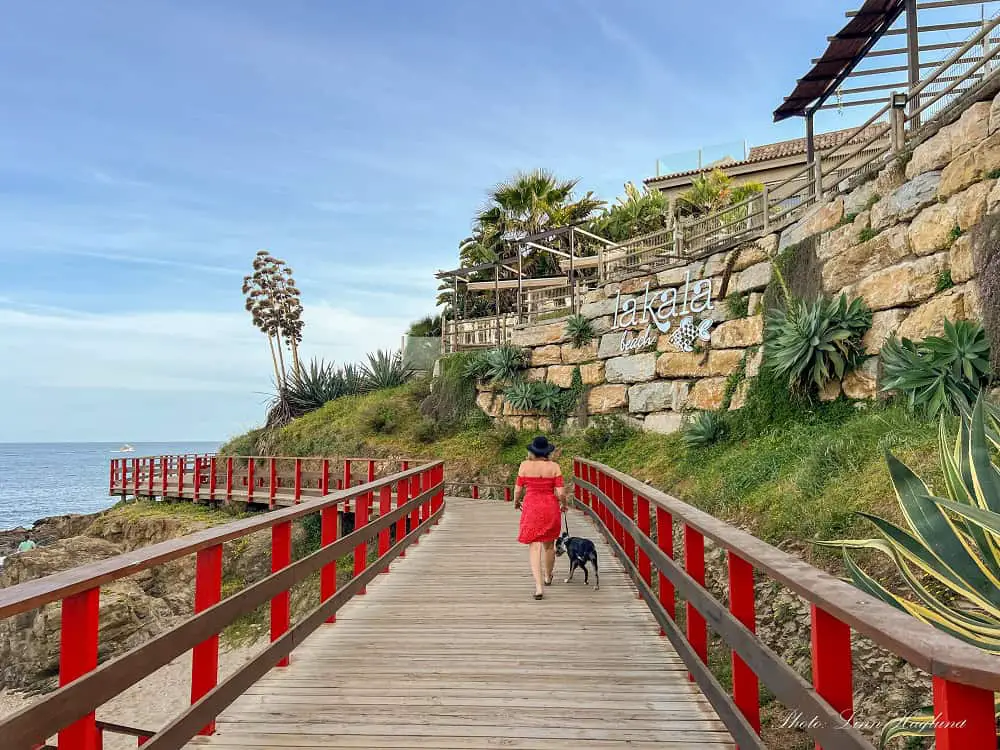 Me walking along Mijas boardwalk in a red dress.