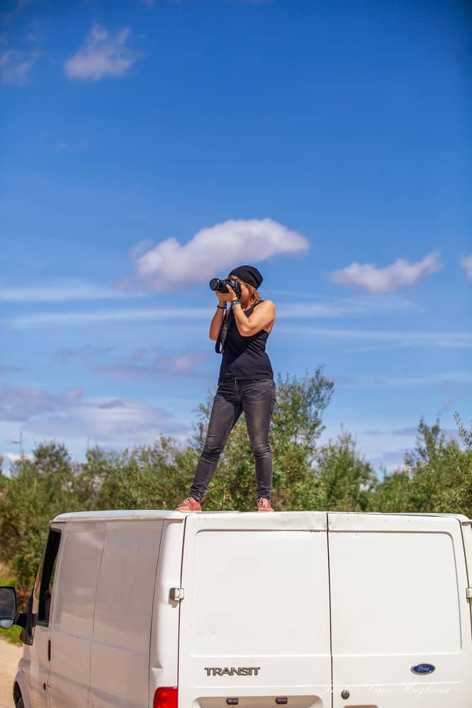 Me living the Van life Spain standing on the van roof taking pictures with my camera.