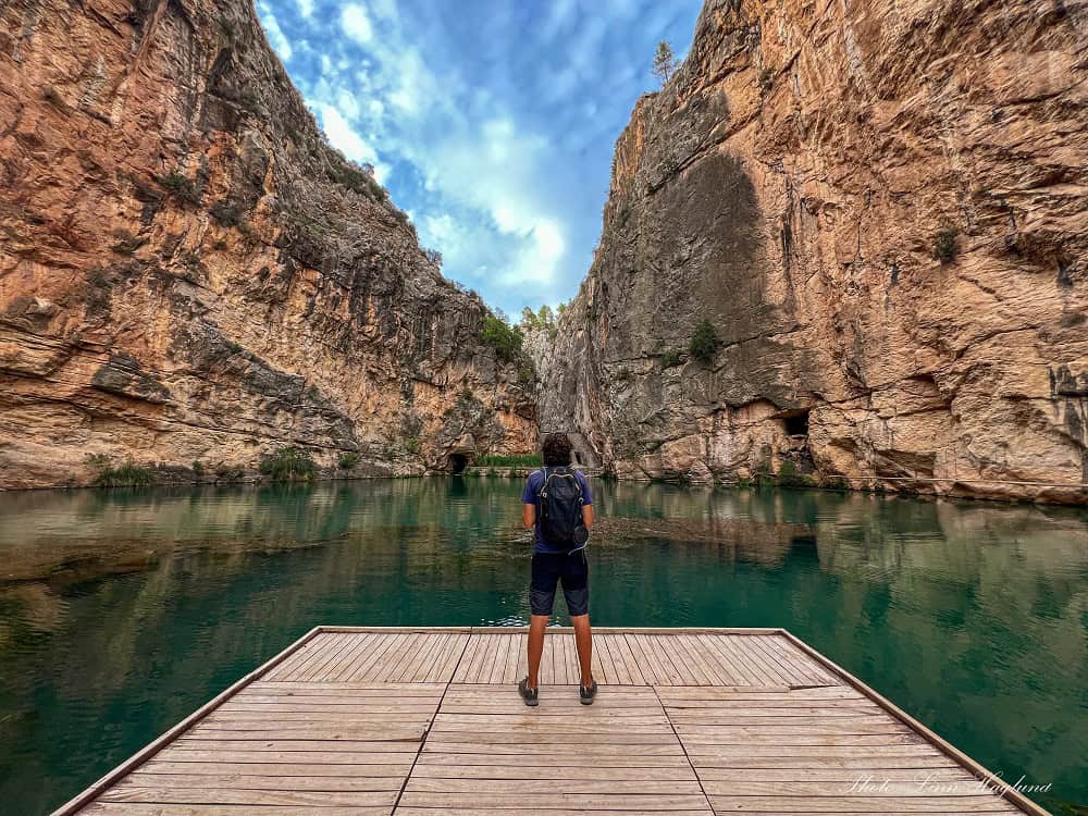 Mohammed standing on a wooden dock looking out at the mesmerizing emerald-green lage of Charco Azul.