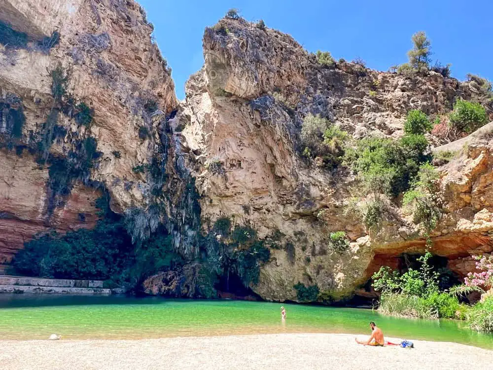 The green lake of Cueva del Turche Valencia with people swimming.