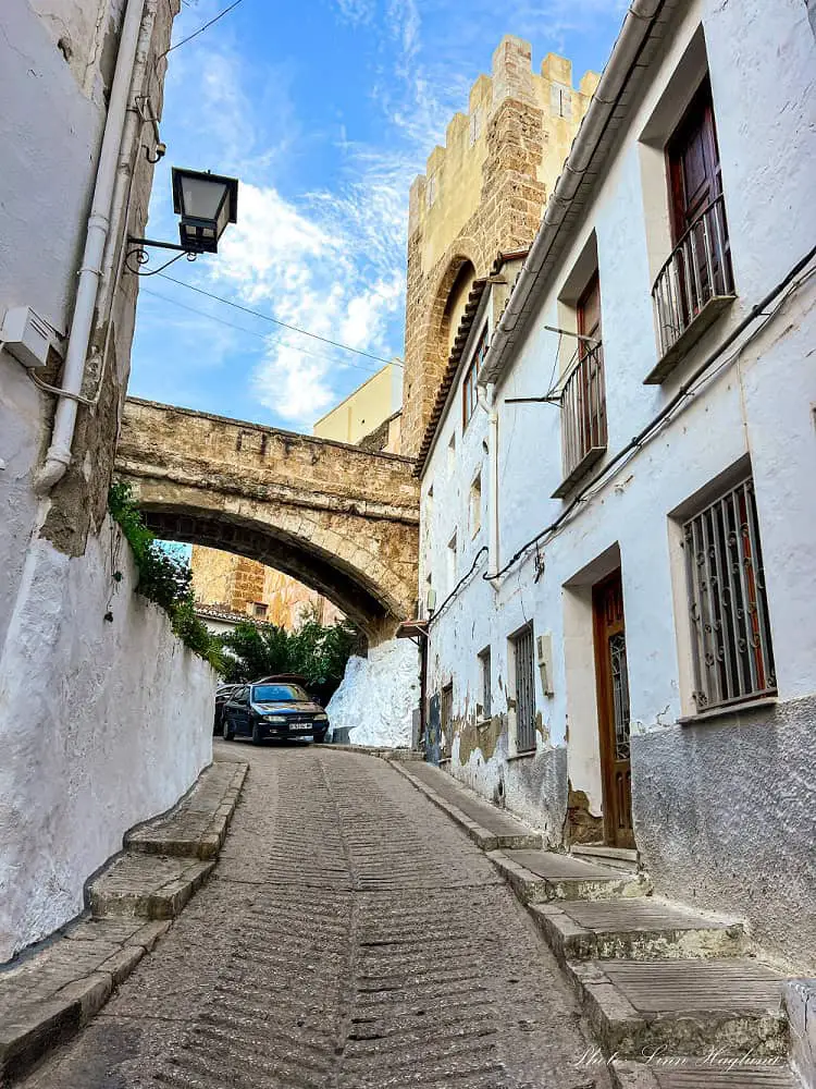Street in Buñol old town with a medieval bridge at the end.