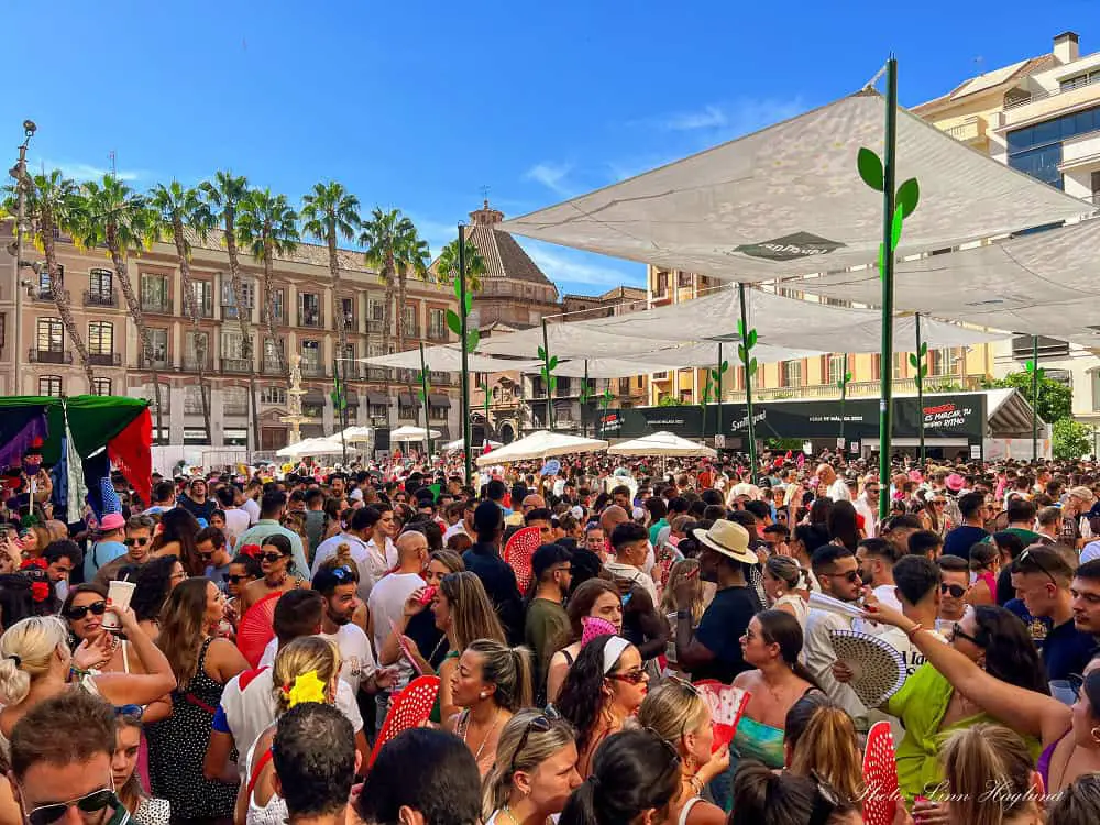 A square full of people dancing and singing during Feria de Malaga.