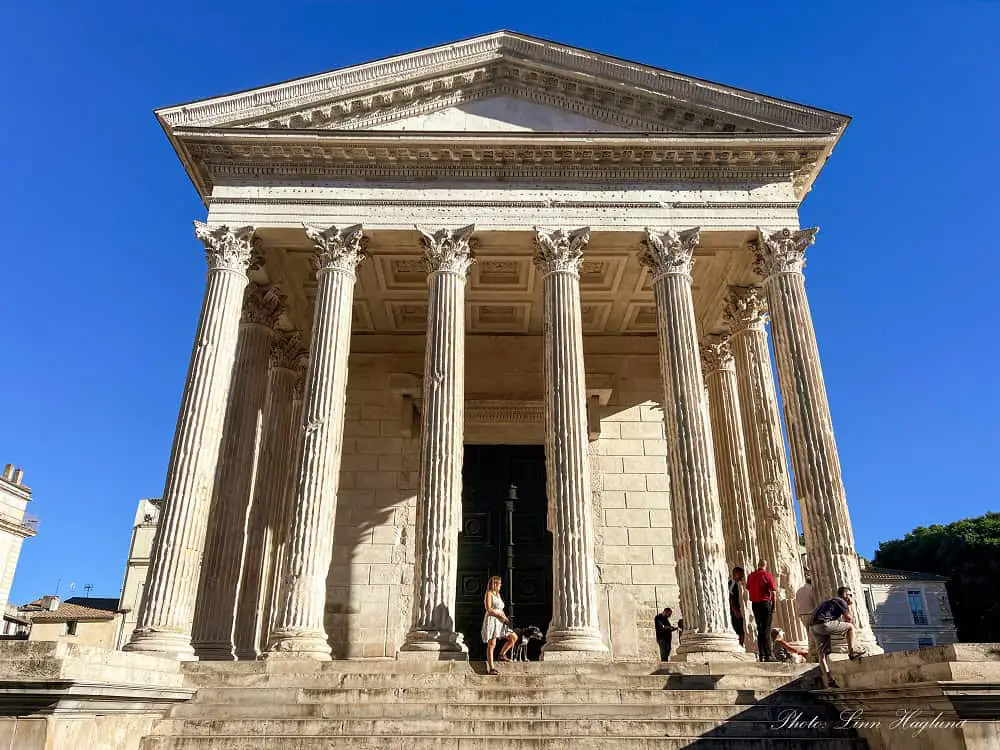 Me and atlas standing next to large columns at Maison Carrée Nimes.