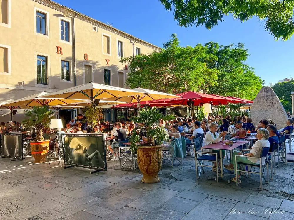 People eating at the outside tables of a busy restaurant in Nimes.