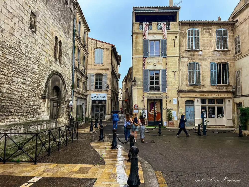 People strolling around Arles old town on a rainy day during their Arles itinerary.