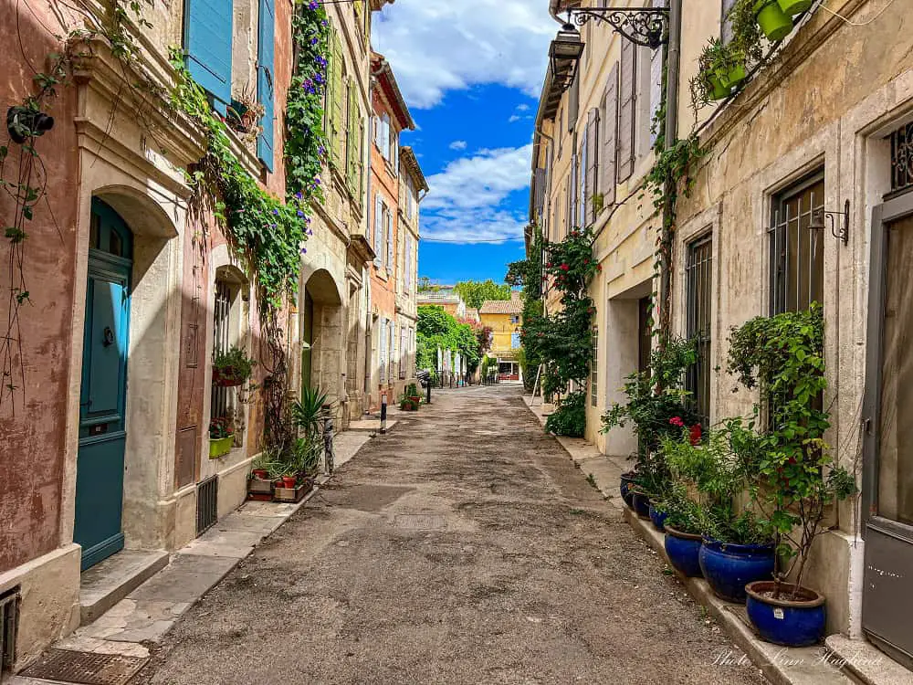 A beautiful cobbled street in Arles lined with pot plants and colorful windows.