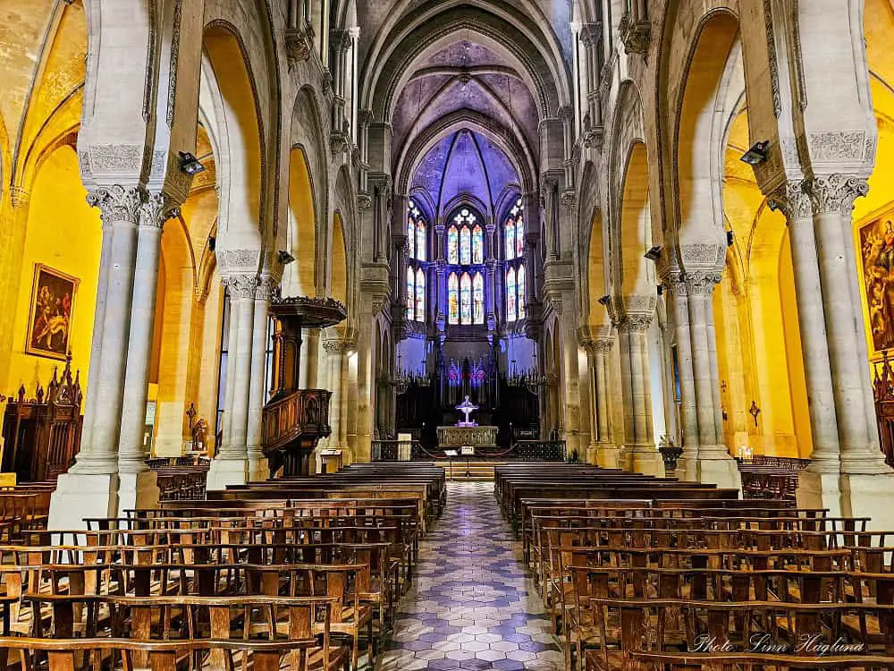 Must-see church when visiting Nimes France with yellow walls, large columns, and stained glass windows.