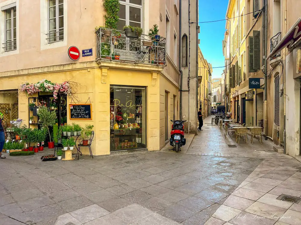 Visit Nimes streets and shops set in pastel colored houses.