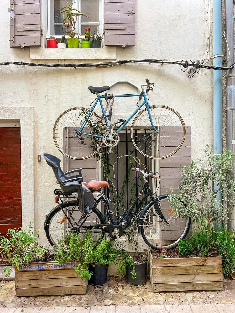 Two bikes hanging on the wall outside a window in La Roquette neighborhood Arles.