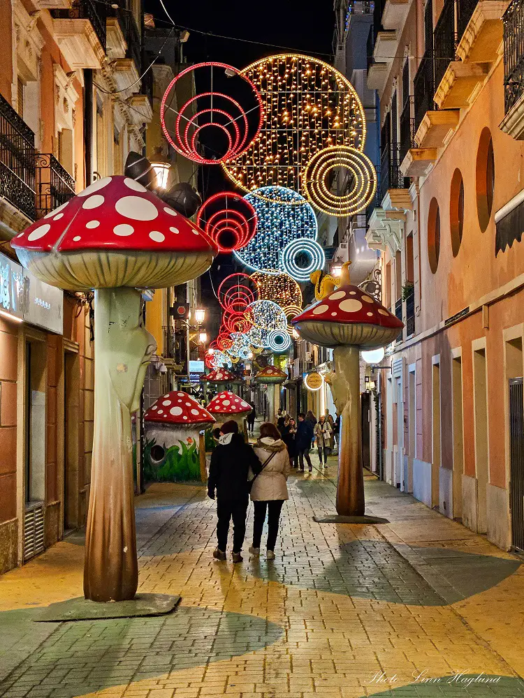 People walking in a festive street with mushrooms in Alicante.