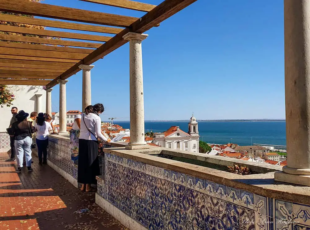 People looking out from a Lisbon viewpoint with beautiful Portuguese tiles which you easily can do with just a day in Lisbon.