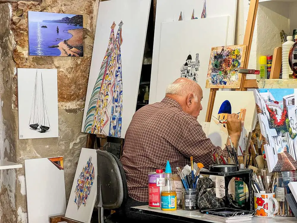 Artist in Altea painting images from the town in his shop.