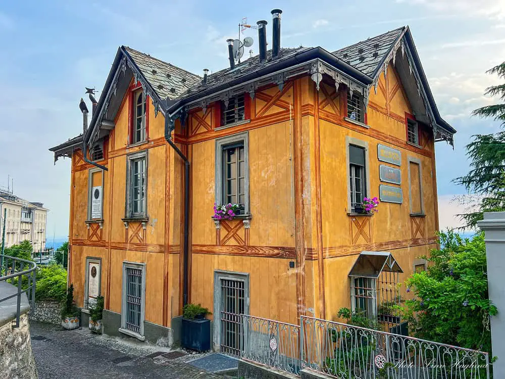 An orange Art Nouveau house with painted details on the walls in the tiny hampet of Brunate in Lake Como. Visiting this village is one of the best things to do in Como Italy.