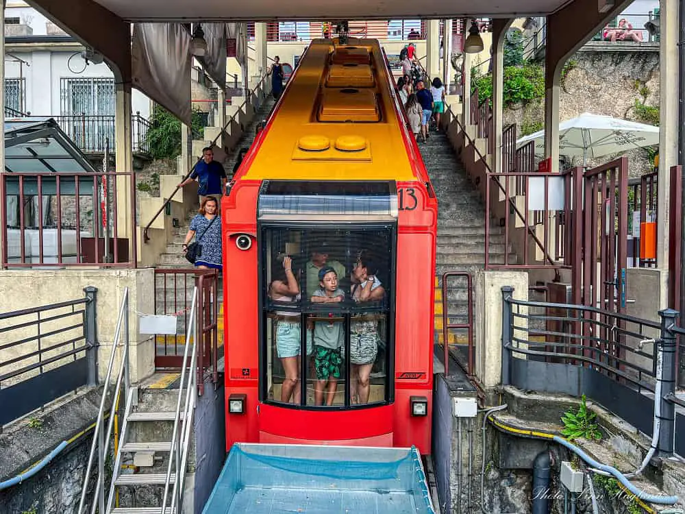 People standing in the front part of the red Brunate Finucular going down to Como.