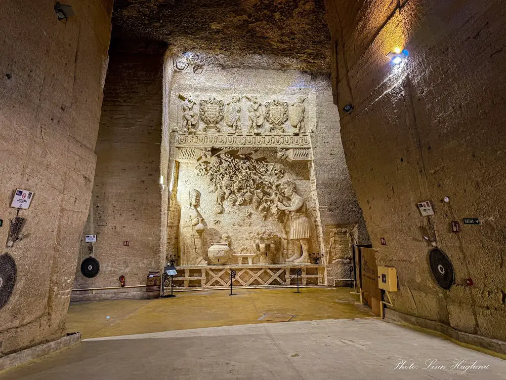 Inside Coto de las Canteras with relics of people picking grapes covering a whole wall. The walls are 25 meters tall and the other walls inside are bare.