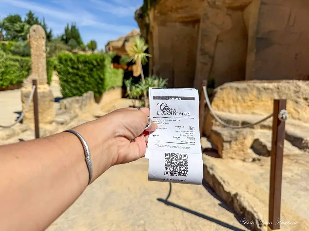 Me holding the entry tickets to Colo de las Canteras in Osuna just after entering the site. It's sunny and you can see the ticket price of 10 Euros for two people.